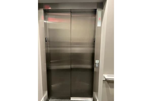 A stainless steel elevator with a red light on the door.